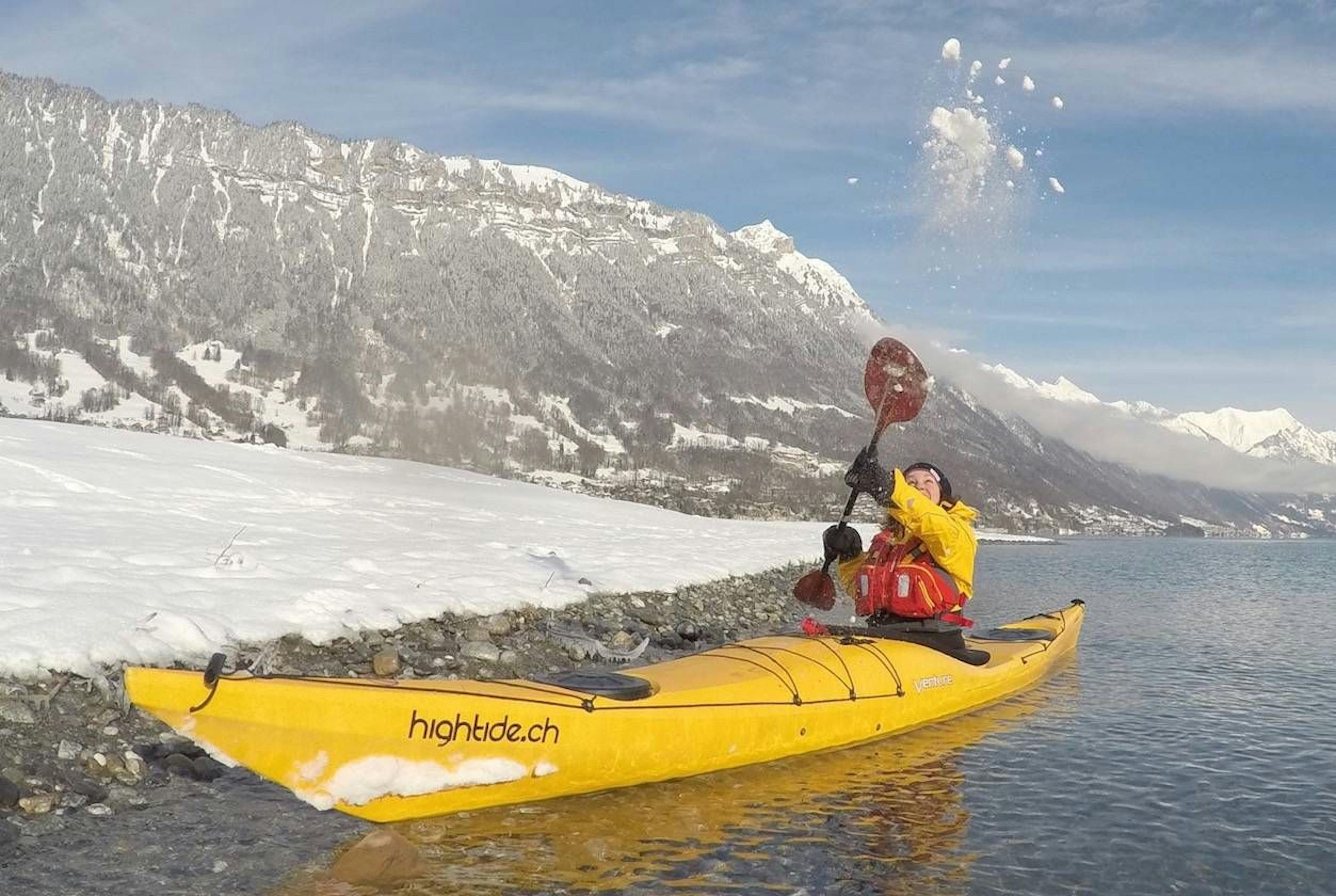 El kayakista en el kayak amarillo salpica agua en el lago Silvretta.
