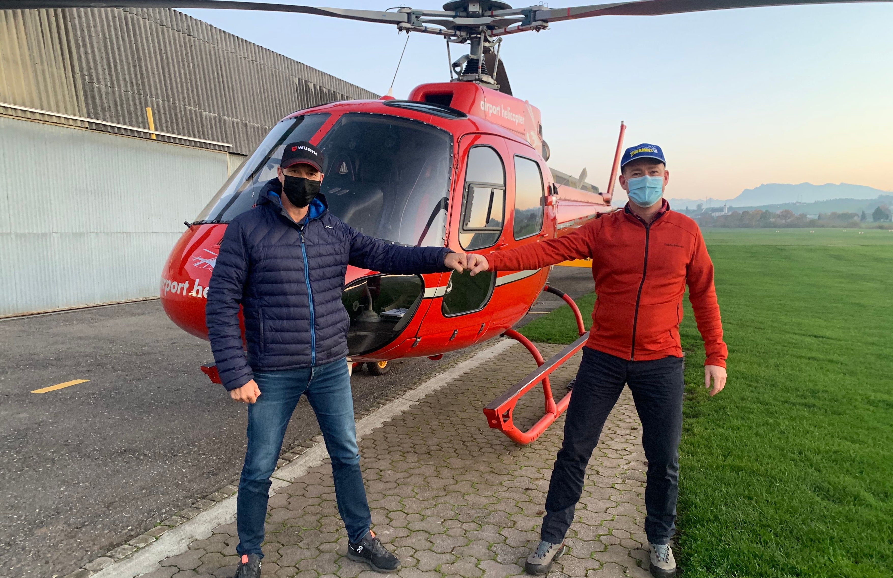 هليكوبتر لوسيرن، رجلان يتبادلان قبضة اليد أمام الهليكوبتر، أرض خضراء