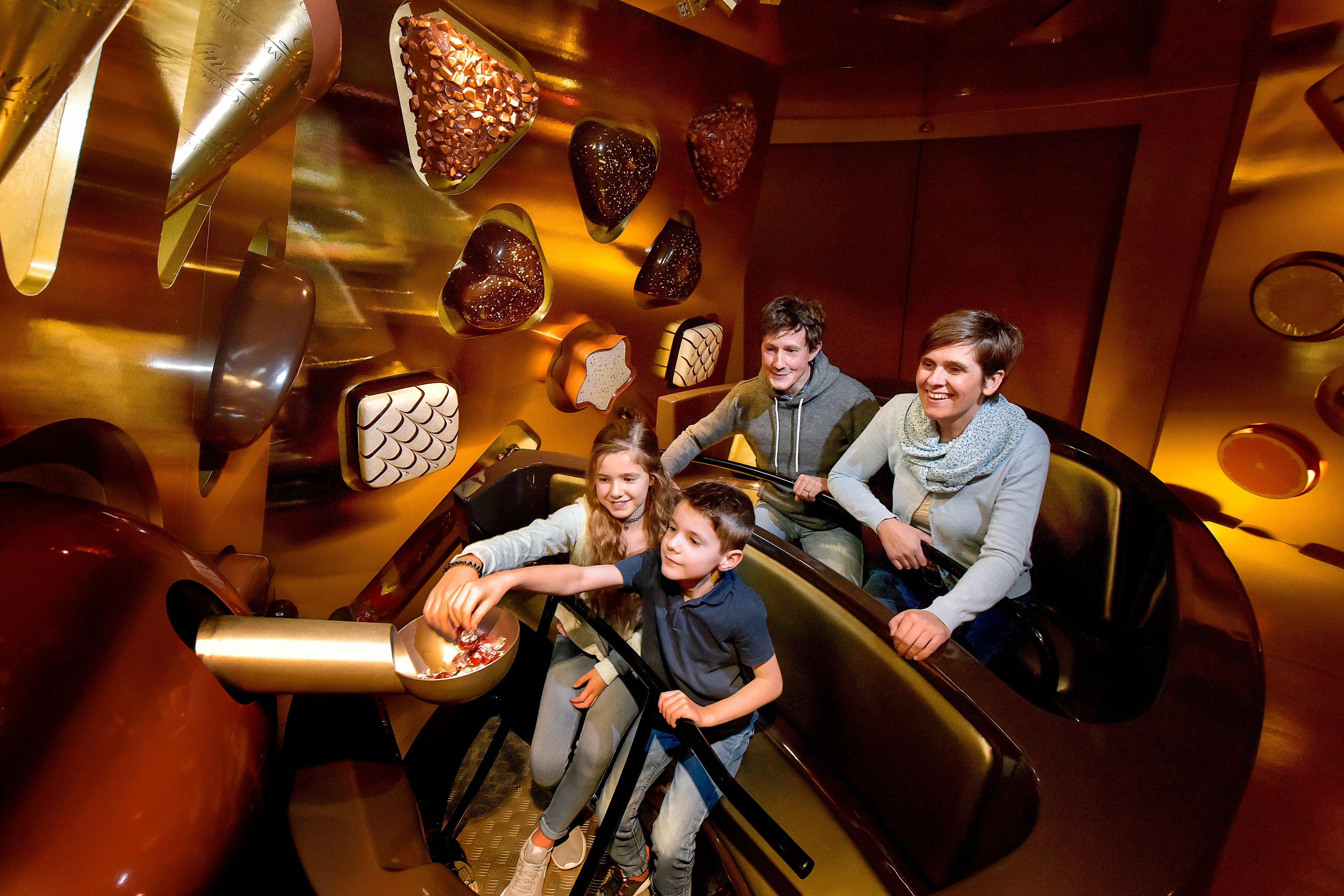 Excursión familiar en una fábrica de chocolate, niños prueban chocolate, ambiente relajado.