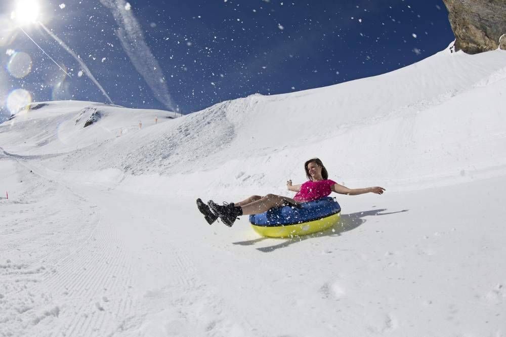 Titlis Ausflug mit Rutschfahrt im Schnee bei sonnigem Wetter.