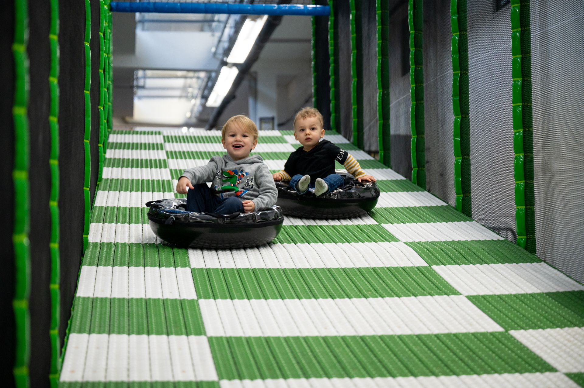 बच्चे हँसी-खुशी खेल मैदान की फिसलपट्टी से नीचे गिर रहे हैं।