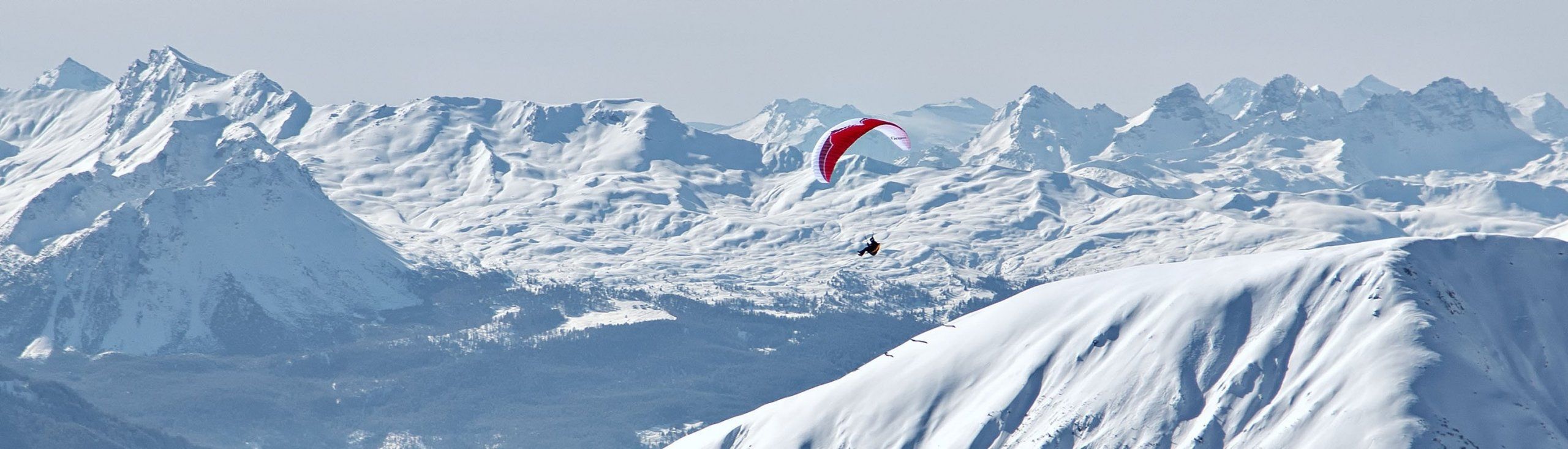 Terjun paragliding di atas gunung bersalji pada musim sejuk 2023.