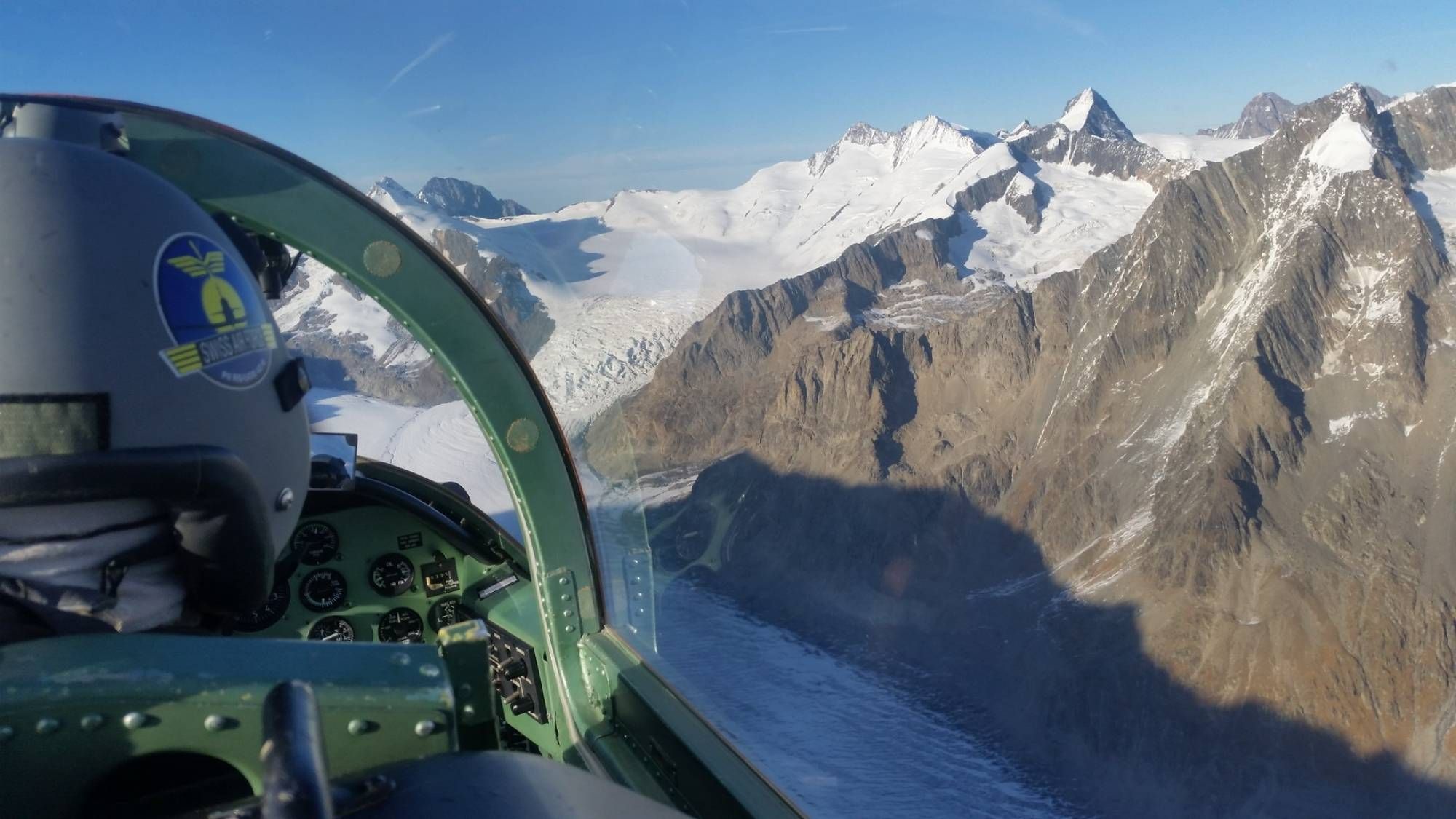 Pemandangan pesawat terbang Pilatus PC7 di atas lereng dan puncak gunung bersalju.