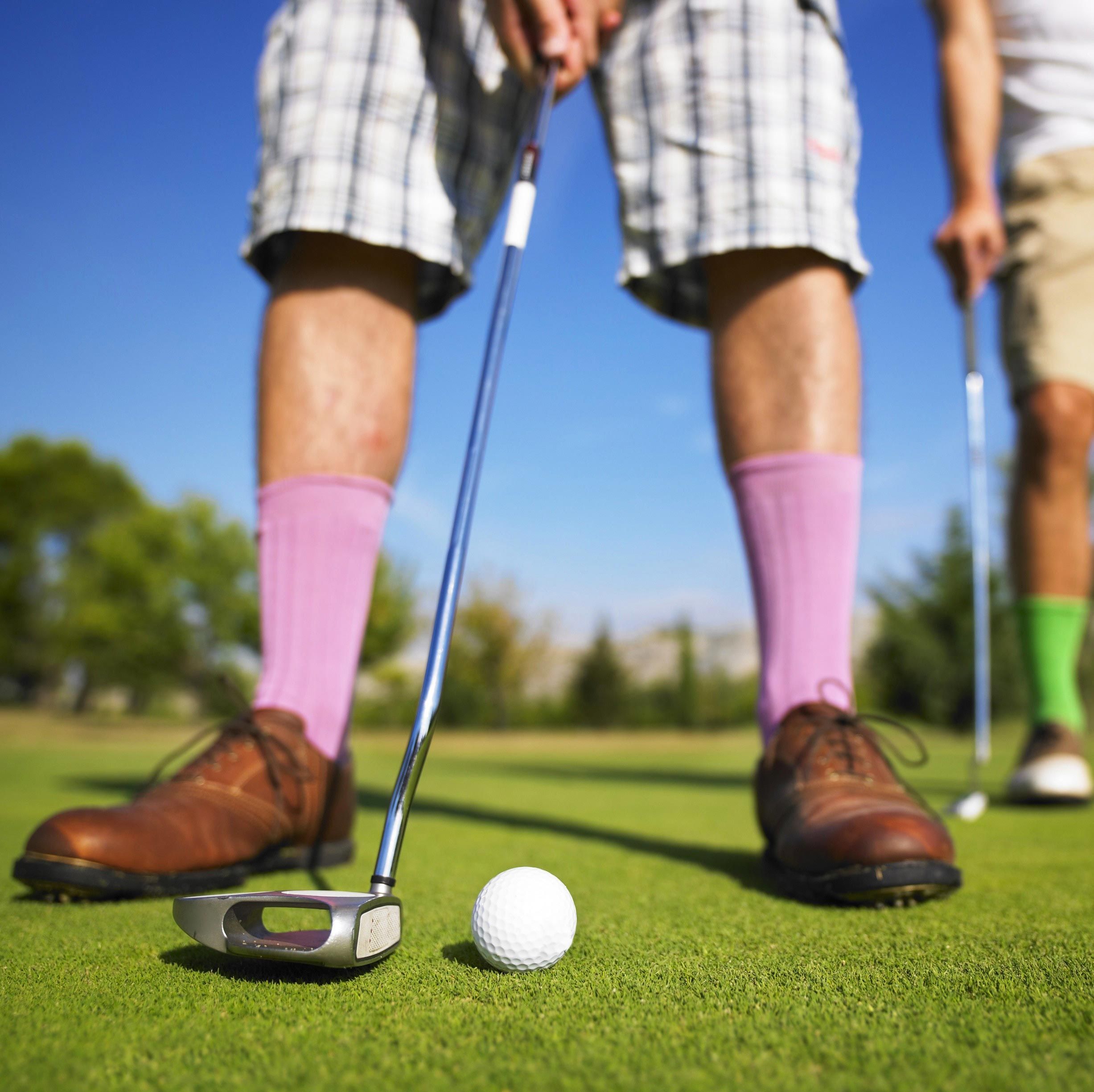 Golfspieler auf dem Golfplatz mit pinken Socken während des Spiels.