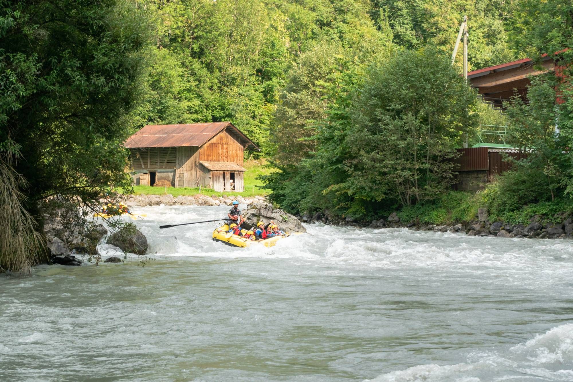 Rafting Sungai Switzerland: Kumpulan di dalam perahu di arus deras disamping alam hijau.