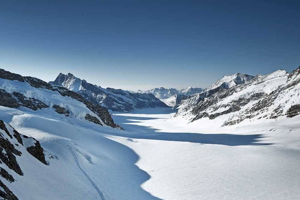 Jungfrau s ledovcem a horami, jasná obloha, lyžařské aktivity