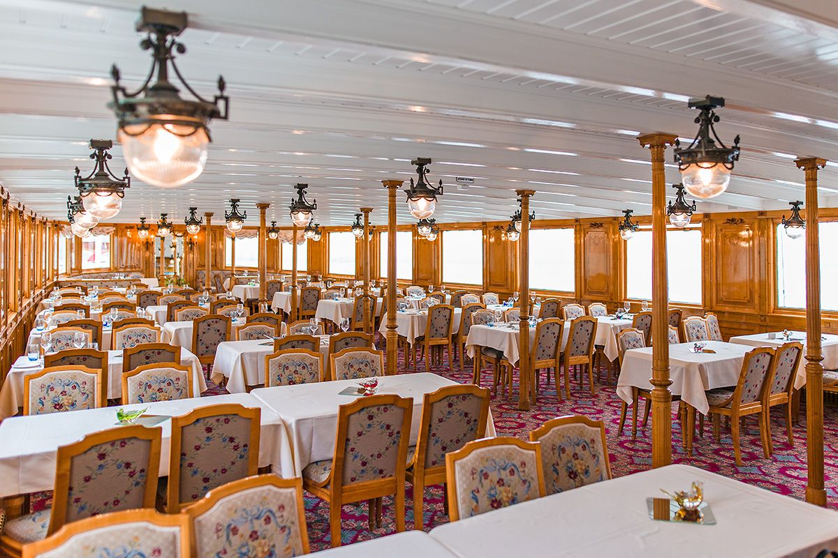 Nave a vapore Belle Époque con arredamento elegante, tavoli e sedie.