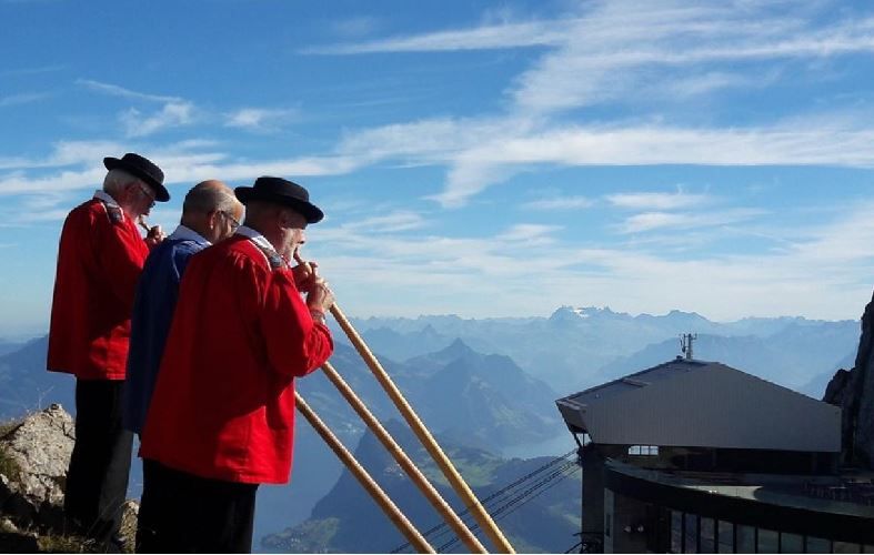 Alphorn players perform on Pilatus with mountain view