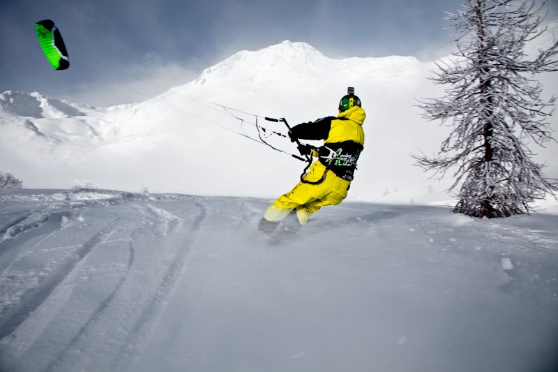 การเล่นสโนว์คิตใน Simplon ในภูมิประเทศที่มีหิมะ นักเล่นสโนว์คิตในชุดสีเหลืองบนหิมะ.