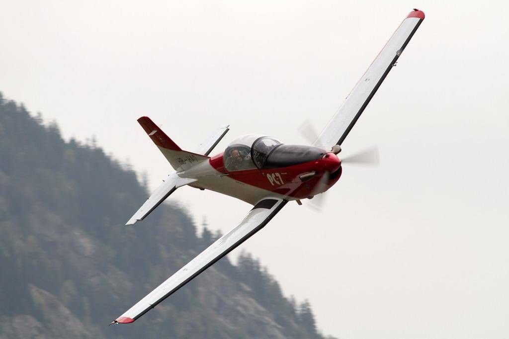 Pesawat Pilatus PC-7 terbang dengan kecepatan tinggi di atas pegunungan, pandangan yang jelas, musim semi 2023.
