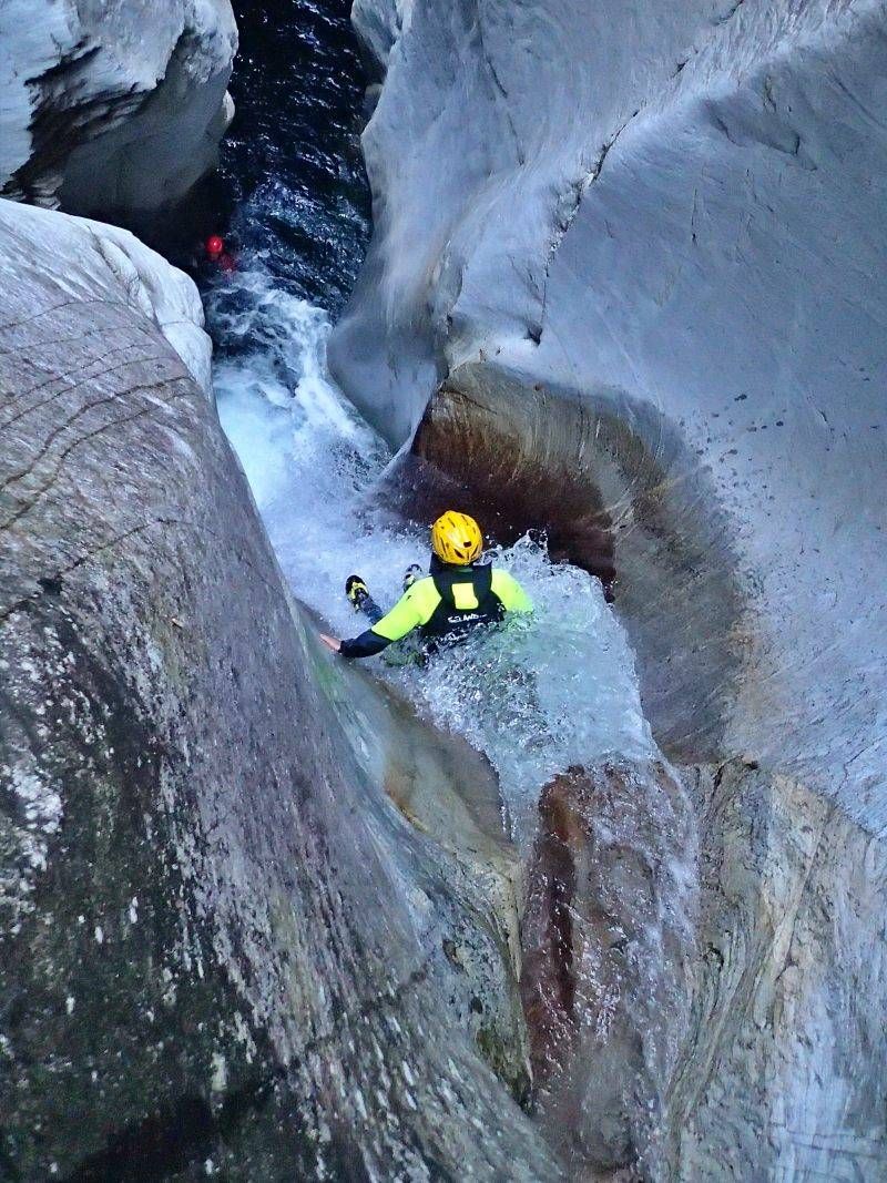 कैनीयोंग लॉड्रीनो: व्यक्ति झरने में पत्थरों के बीच पानी में फिसल रहा है।