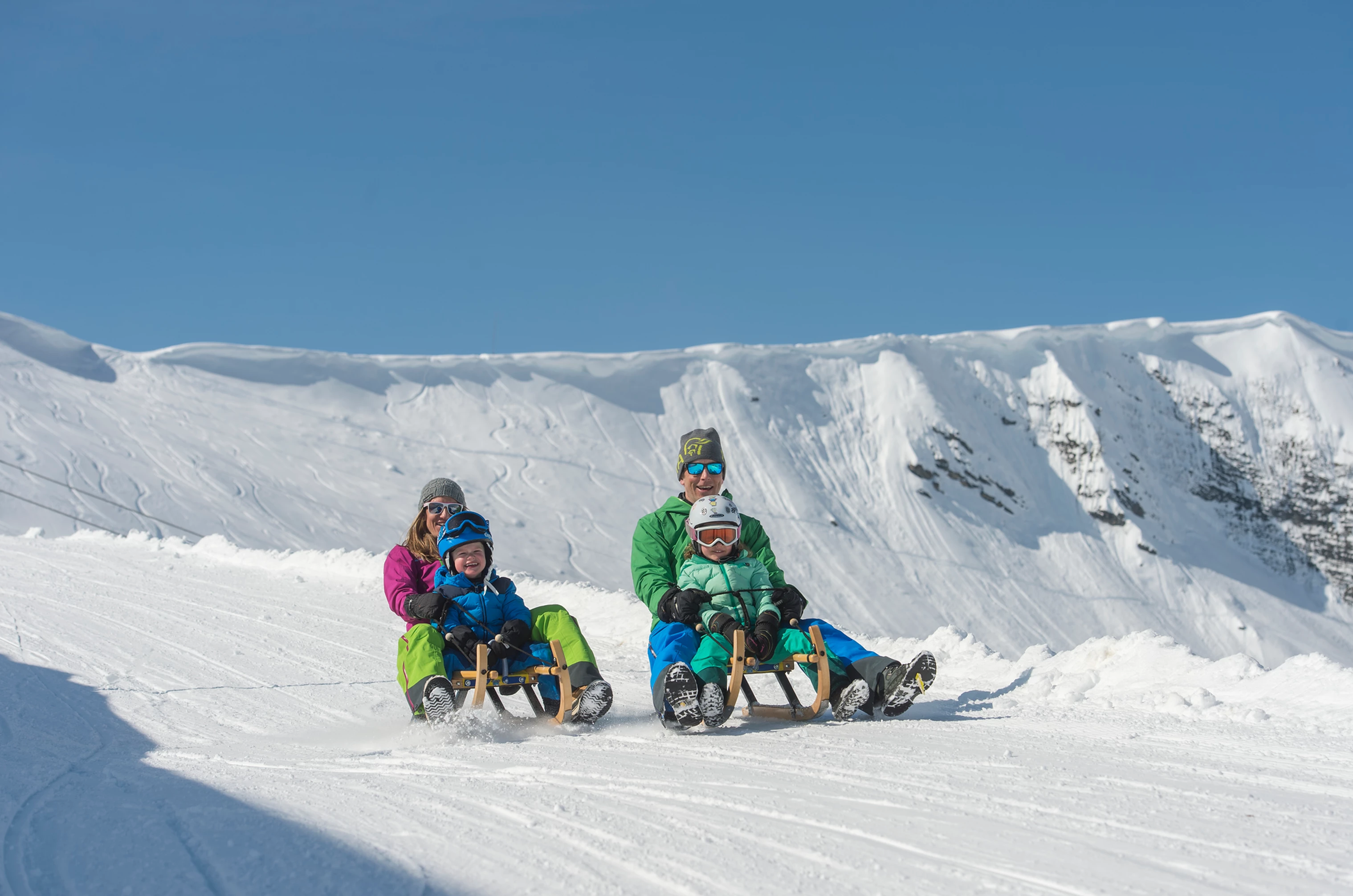 Famille en luge sur la Tschentenalp, ciel bleu, neige
