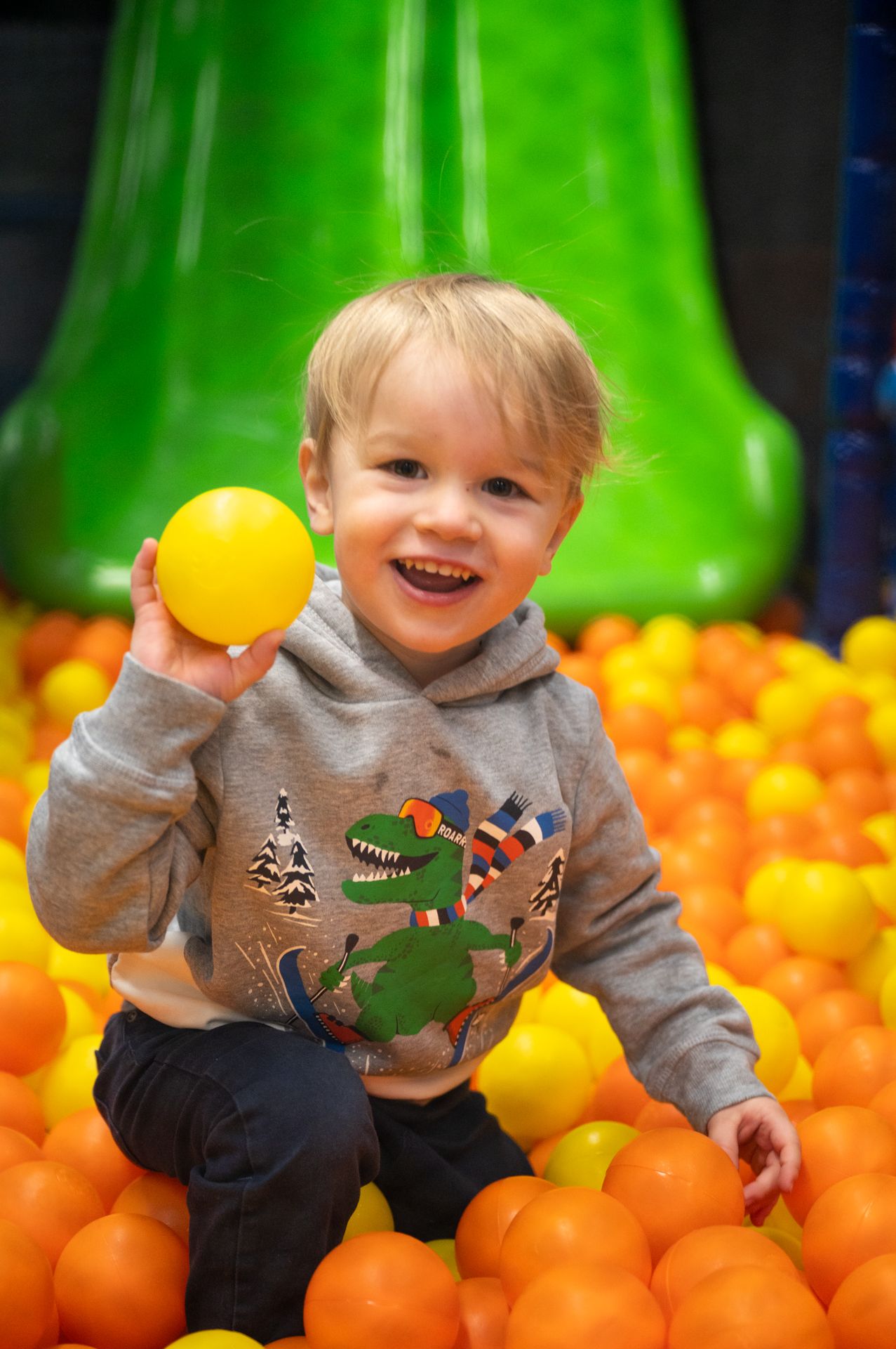 बच्चा पीले गेंद के साथ इनडोर बच्चों की गेंद पूल में खेल रहा है