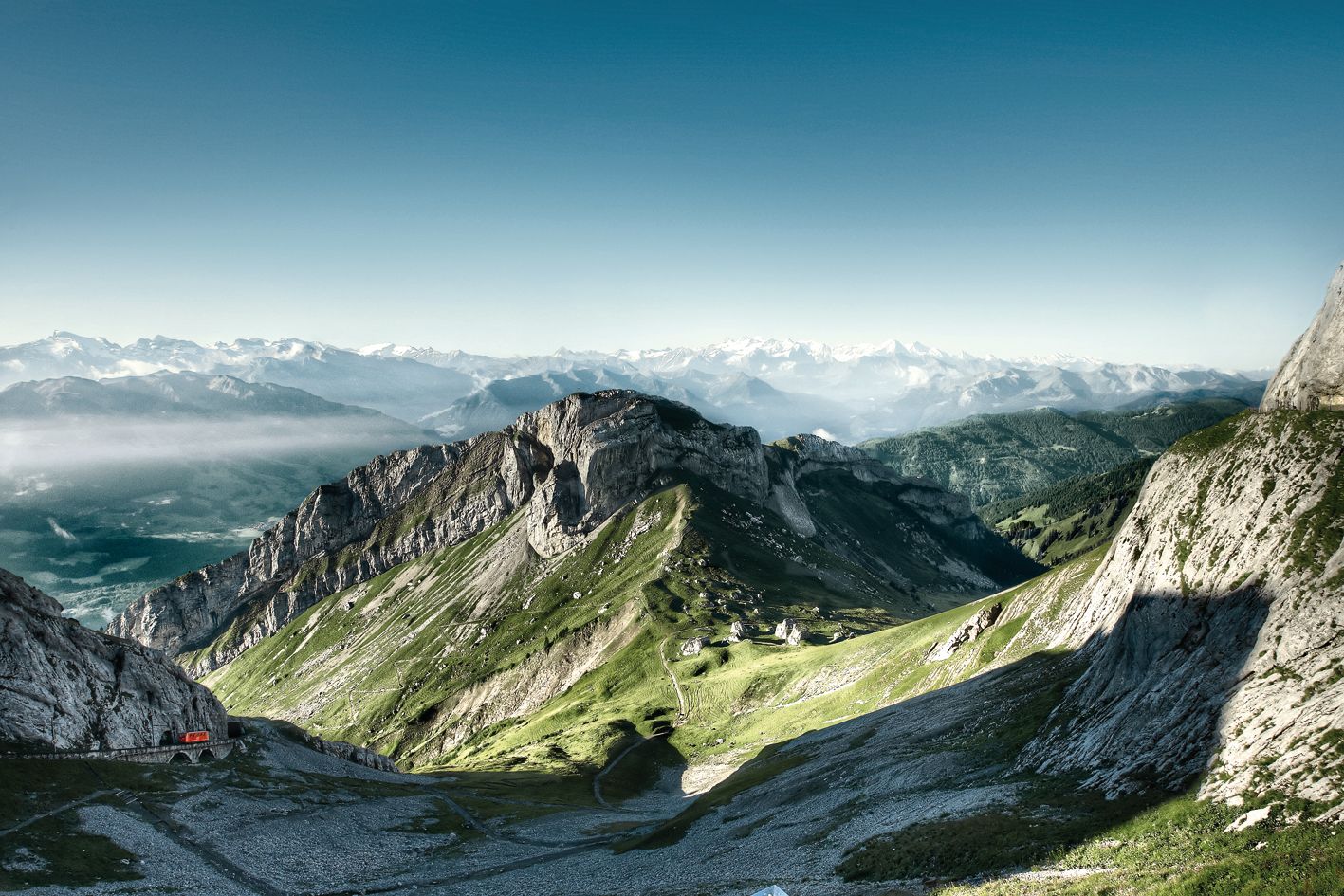 Ausblick Pilatus mit grünen Bergen und Alpen im Hintergrund, klare Sicht