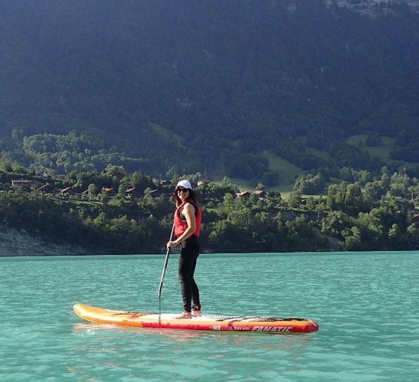 Stand-up-Paddle-Tour auf dem Brienzersee, Frau paddelt in türkisfarbenem Wasser, sommerlicher Tag.