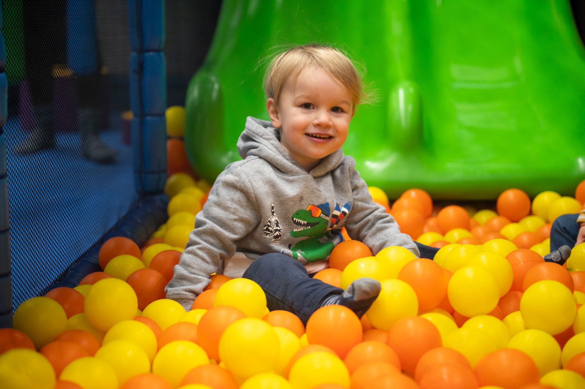 बच्चों के साथ रंगीन गेंदों वाला इनडोर खिलौने का मैदान, स्लाइड के साथ खेल क्षेत्र, खुशमिजाज माहौल