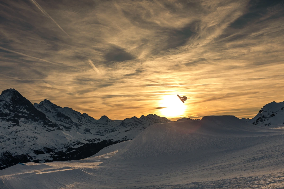 Grindelwald First: Skier jumps in the snow park before the setting sun in the Alps.