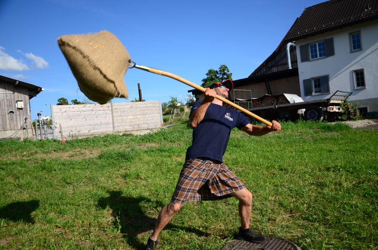 在苏格兰的高地运动会上扔袋子。一个参与者在草地上扔一个重袋子