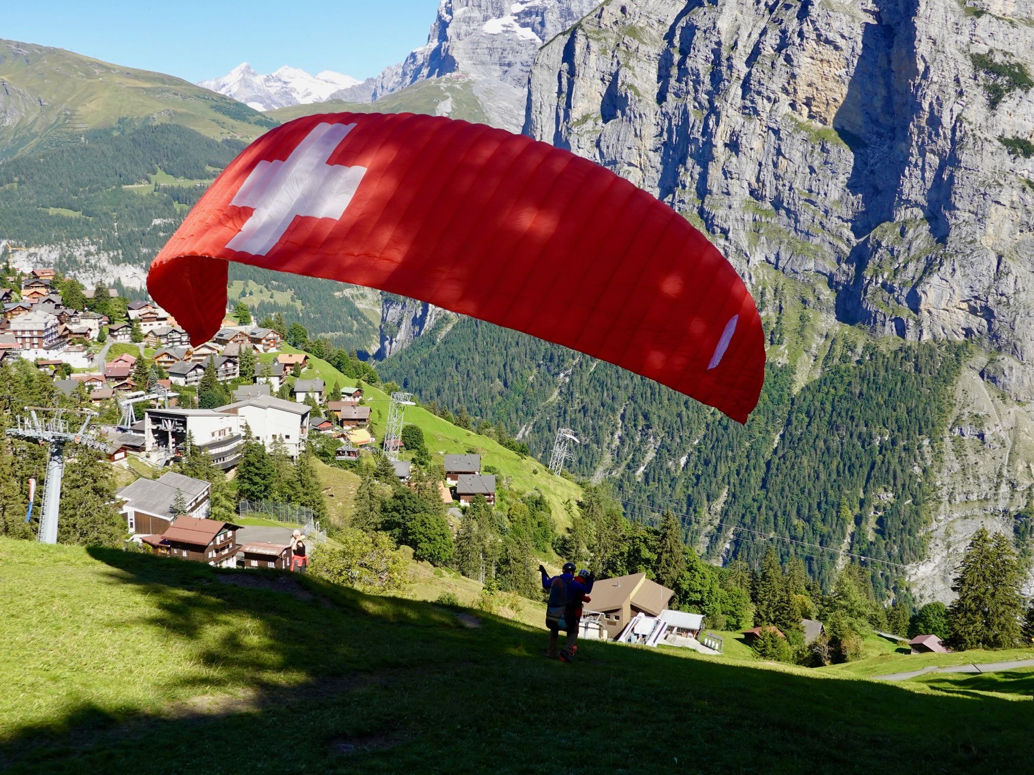 Paragliding in Lauterbrunnen with red parachute over the landscape.
