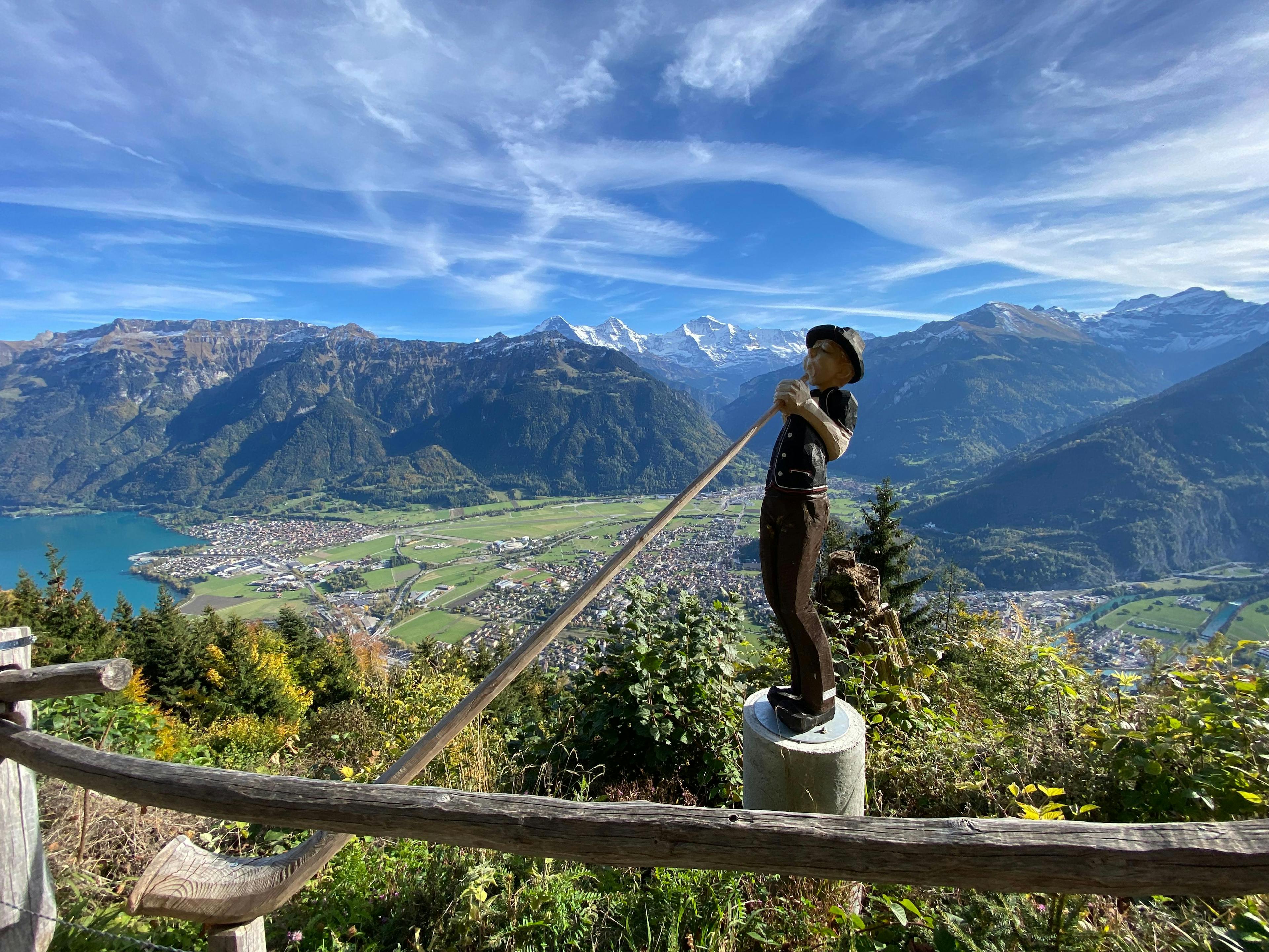 Virtual travel companion in Lauterbrunnen with a view of the mountains and a hiker. The sky is clear and the landscape is green.