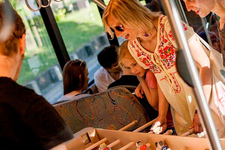 Gruempeltournooi Kickerplezier Zwitserland, deelnemers spelen aan een kickertafel in een bus bij zonnig weer.
