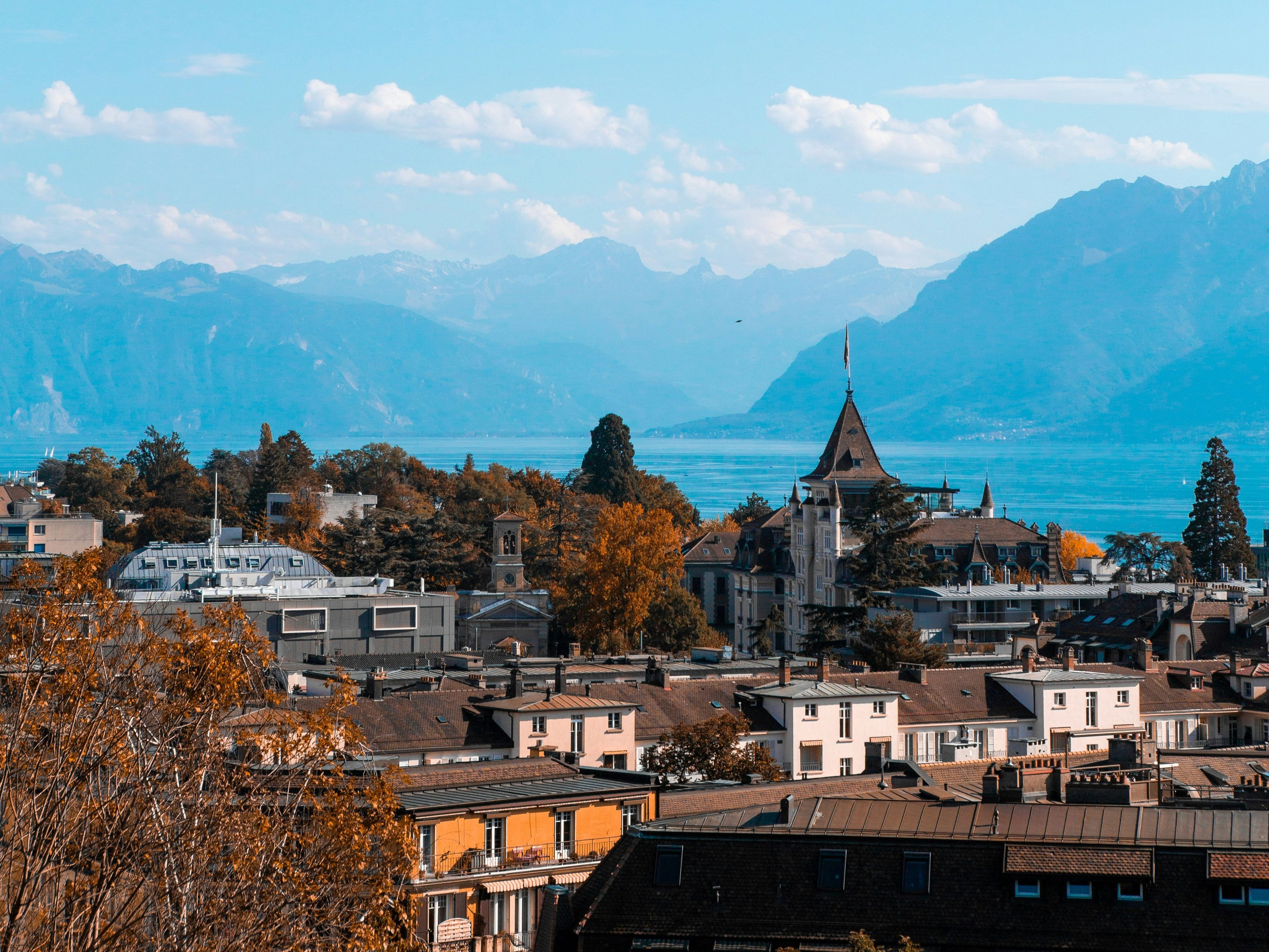लेक जेनेवा का शानदार दृश्य: पहाड़ों और पतझड़ के रंगों से भरी सुंदर शहर की झलक, यात्रा और आराम के लिए आदर्श।