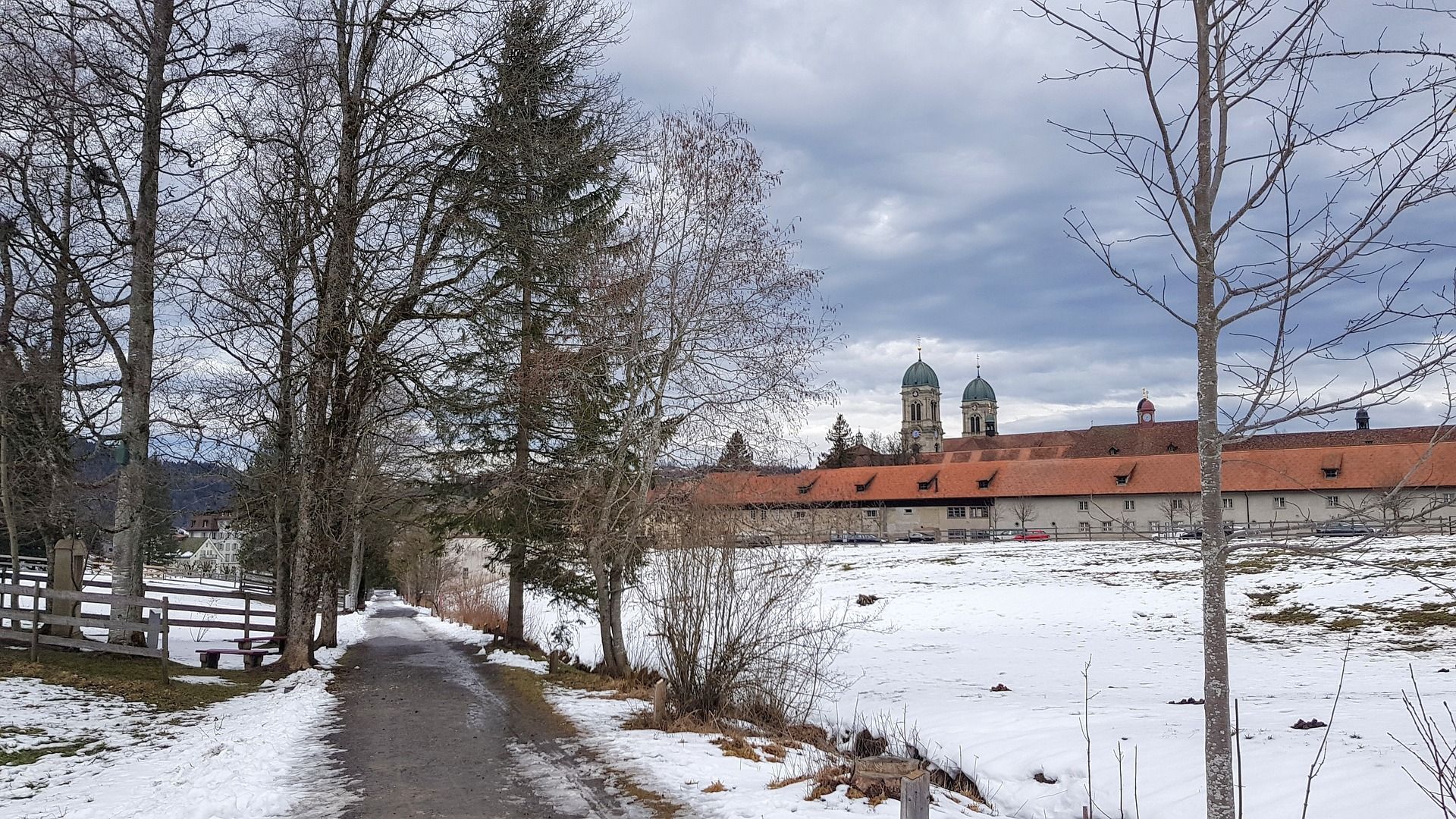 Einsiedeln kloster: naturskönt vinterlandskap med snötäckta vägar och träd.