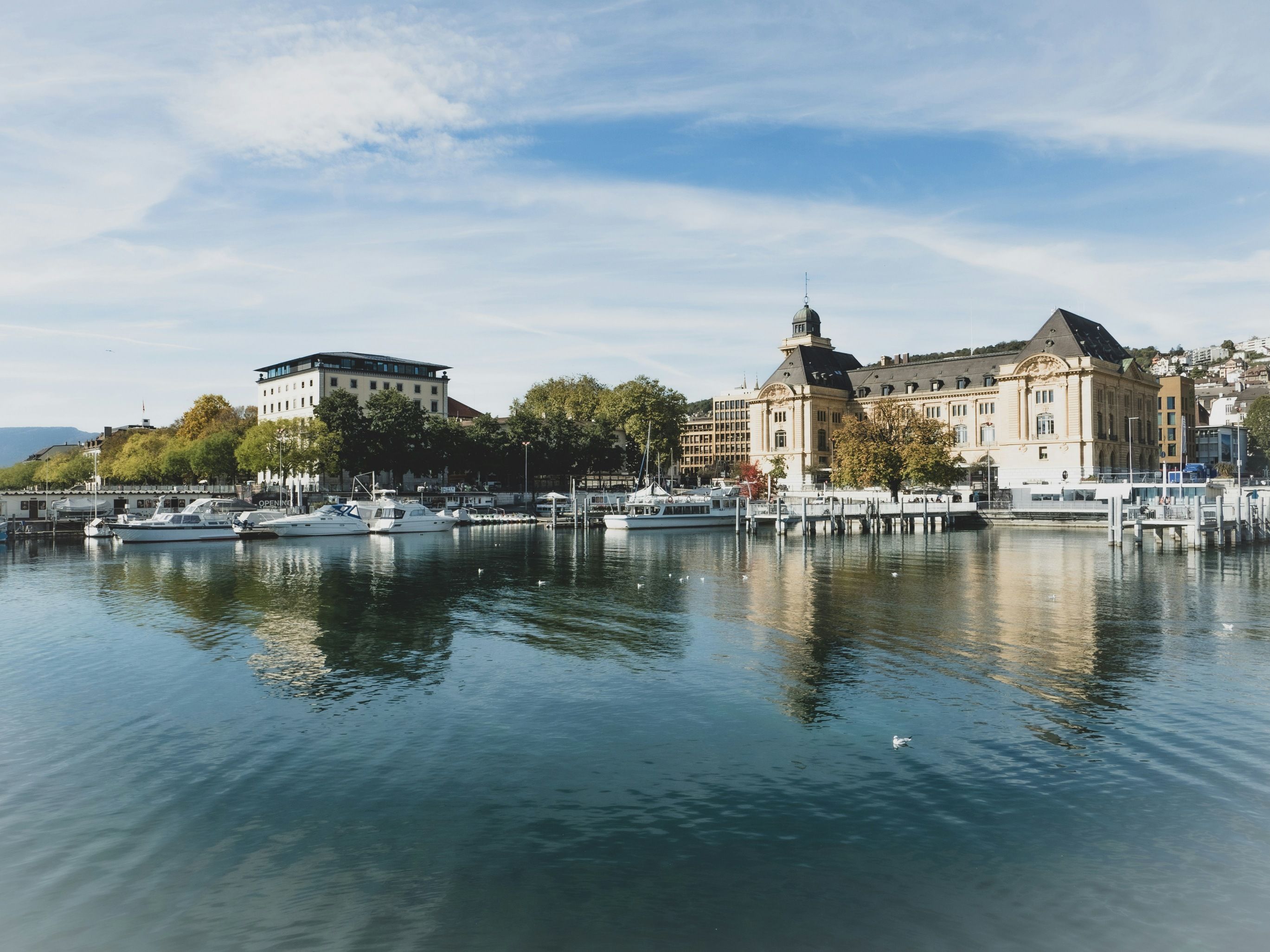 Neuchâtel: Pelabuhan yang indah dengan permukaan air yang jernih dan bangunan bersejarah di tepi pantai.
