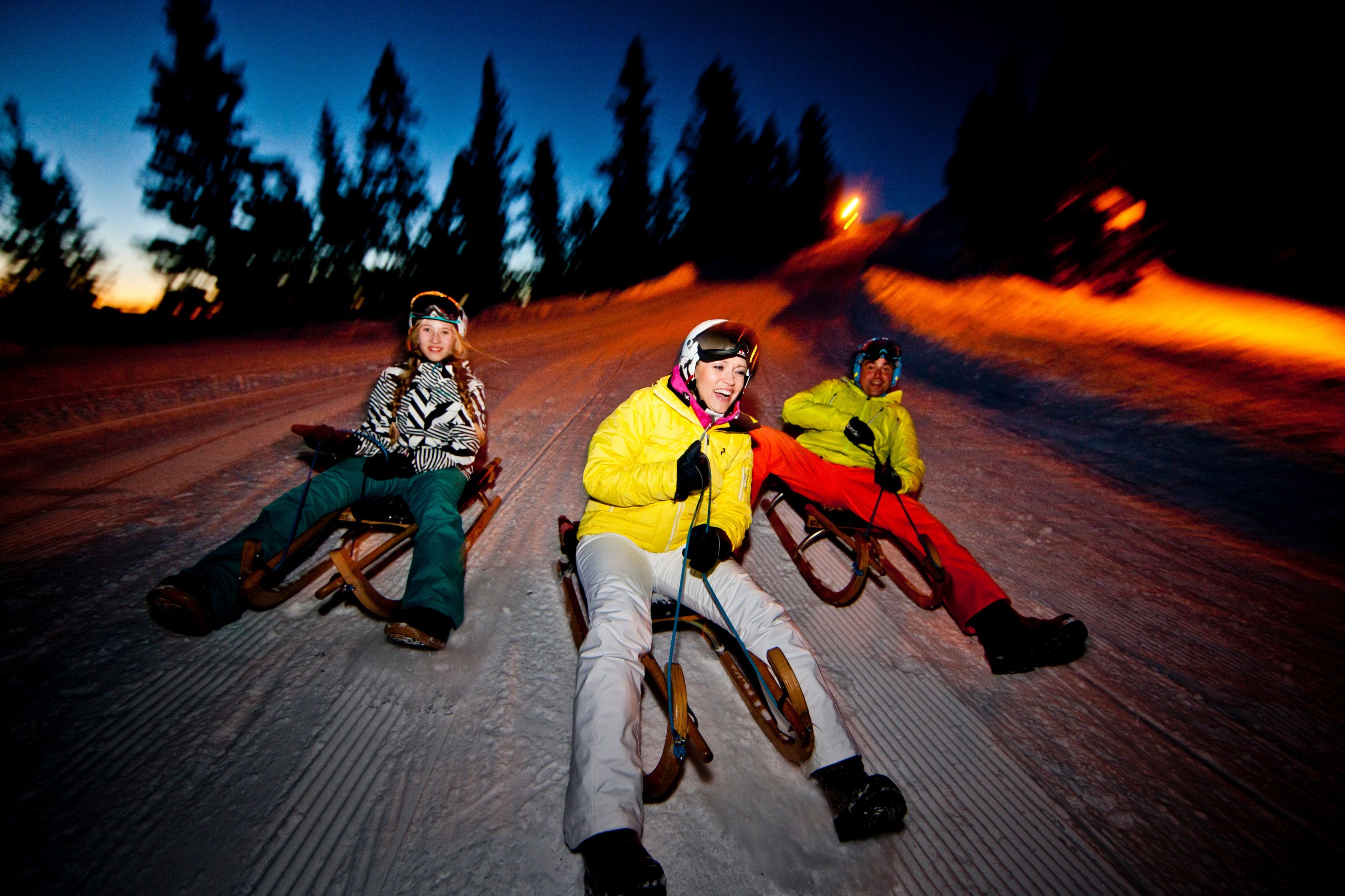 Tobogganing de noche en Suiza, descenso seguro en invierno con amigos y familia.