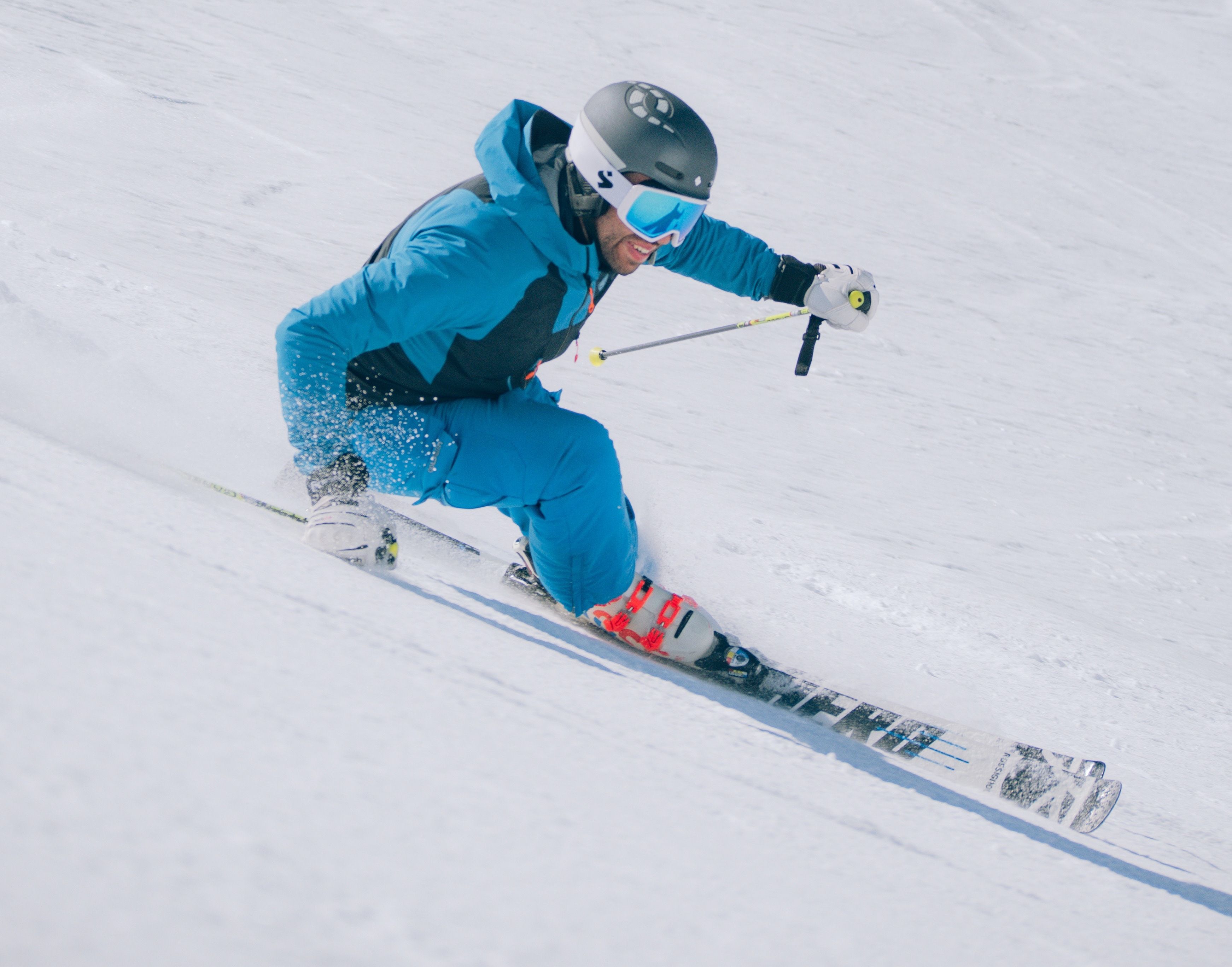 Narciarstwo na świeżym śniegu, zachwycony narciarz w niebieskim sprzęcie.