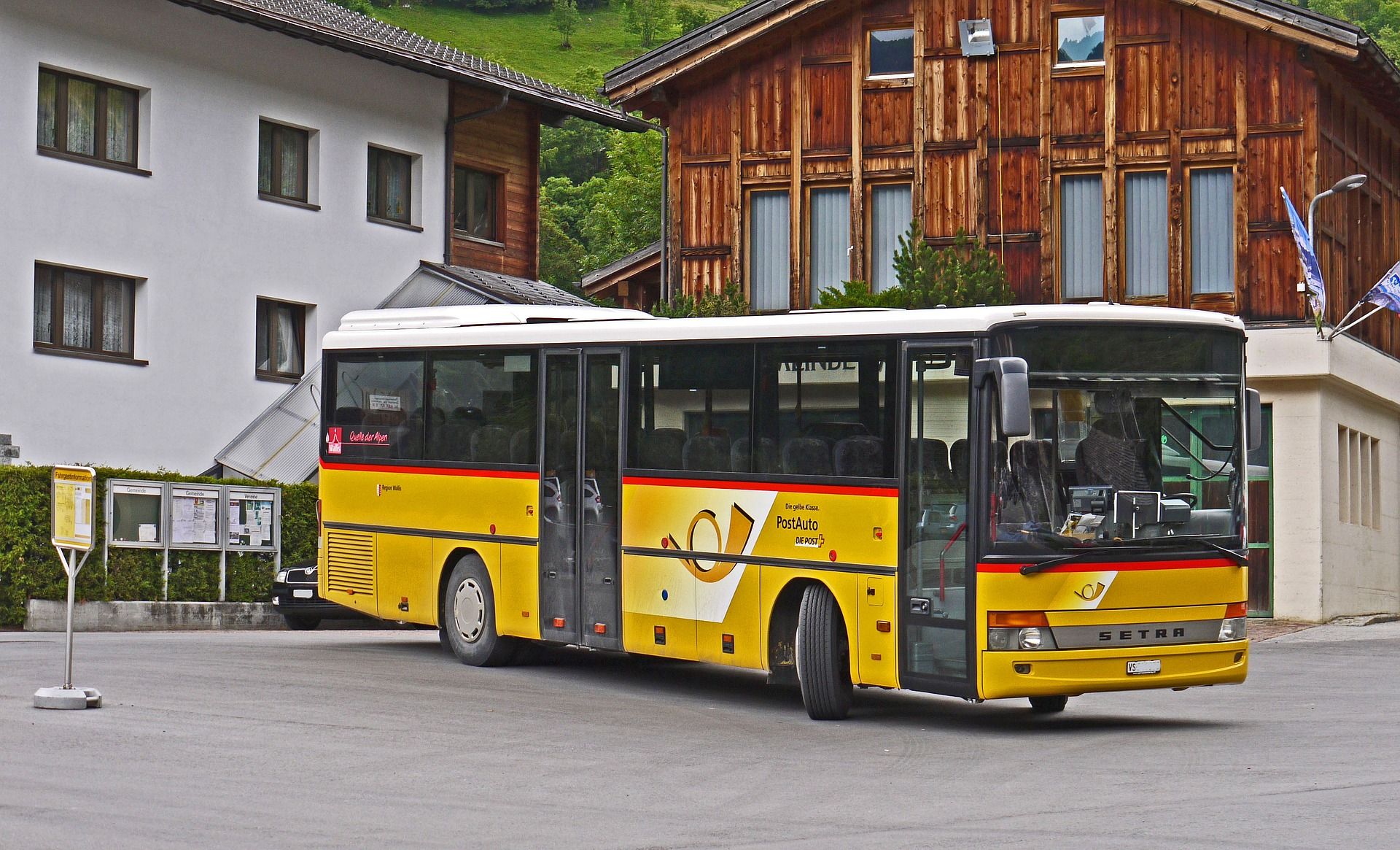 Postauto: Žlutý cestovní autobus v malebném prostředí s horami, ideální na výlety.
