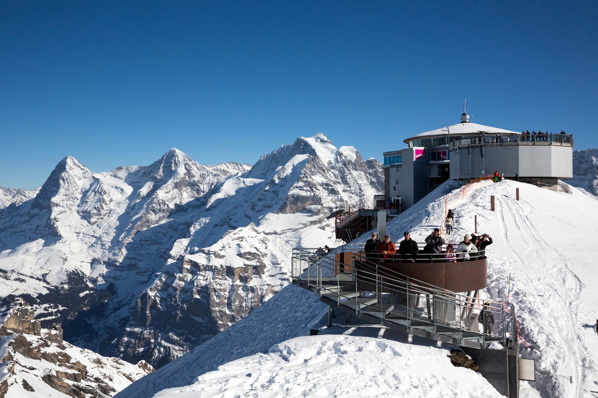 Schilthorn: Panorama-uitzicht op de toppen van de Alpen in de winter met bezoekers op het uitkijkplatform.