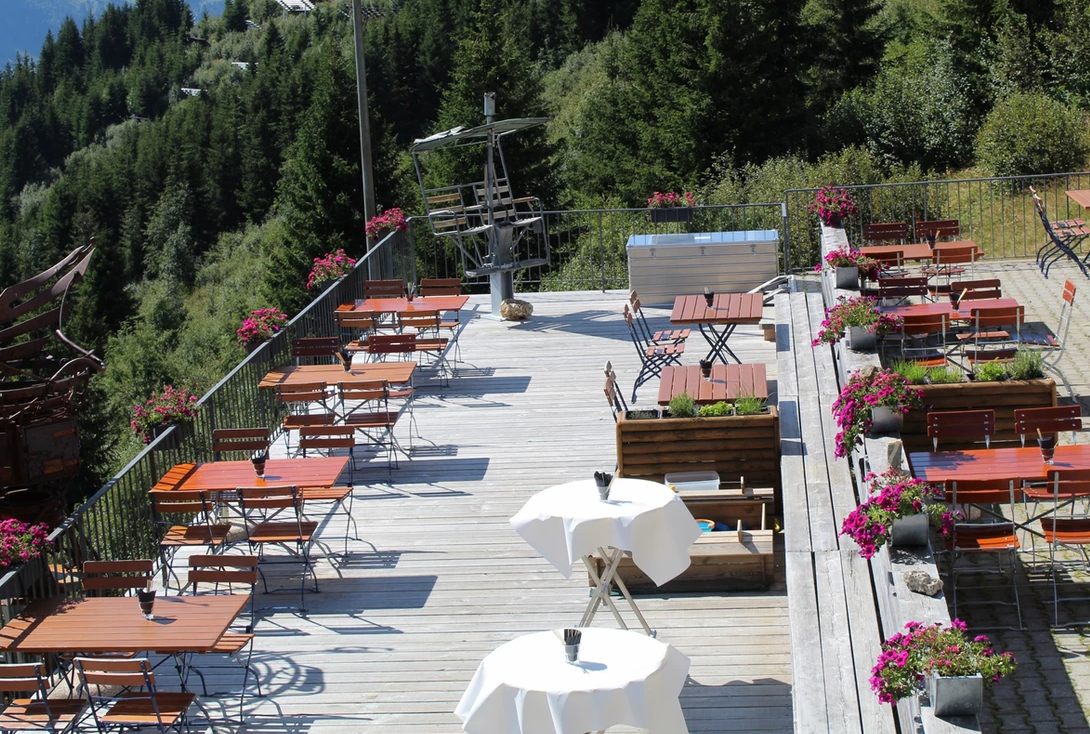 Ristorante Tschentenalp con terrazza, tavoli di legno e fiori