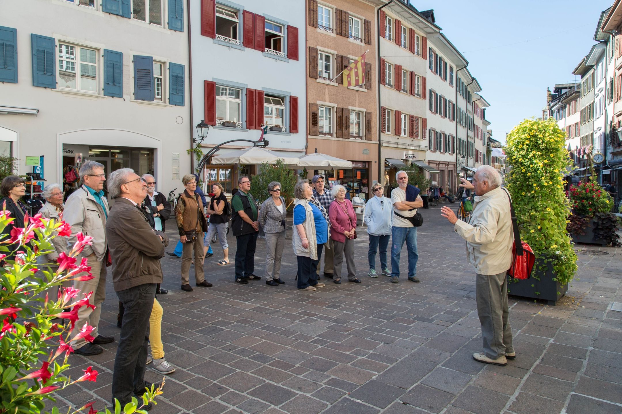 Ξεναγός στην πόλη του Ράινφλεντεν: Ομάδα ακούει τον ξεναγό σε μια ηλιόλουστη πλατεία.