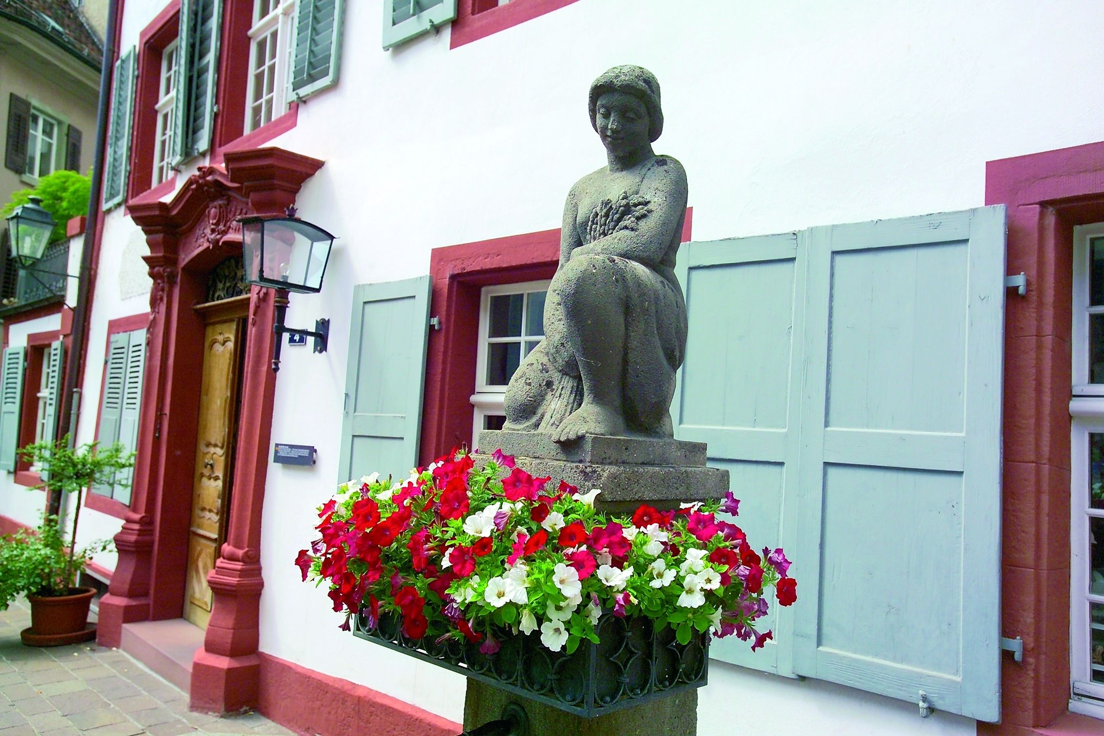Kvinnoskulptur med blommor framför historiska byggnader