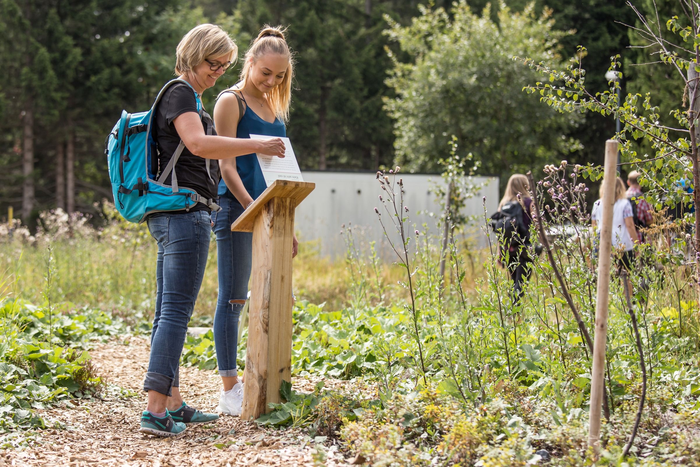 Μαραθώνιος Ένωση Μορί: Δύο γυναίκες διαβάζουν σε πινακίδα πληροφόρησης στη περιοχή μερικών λιμνών.