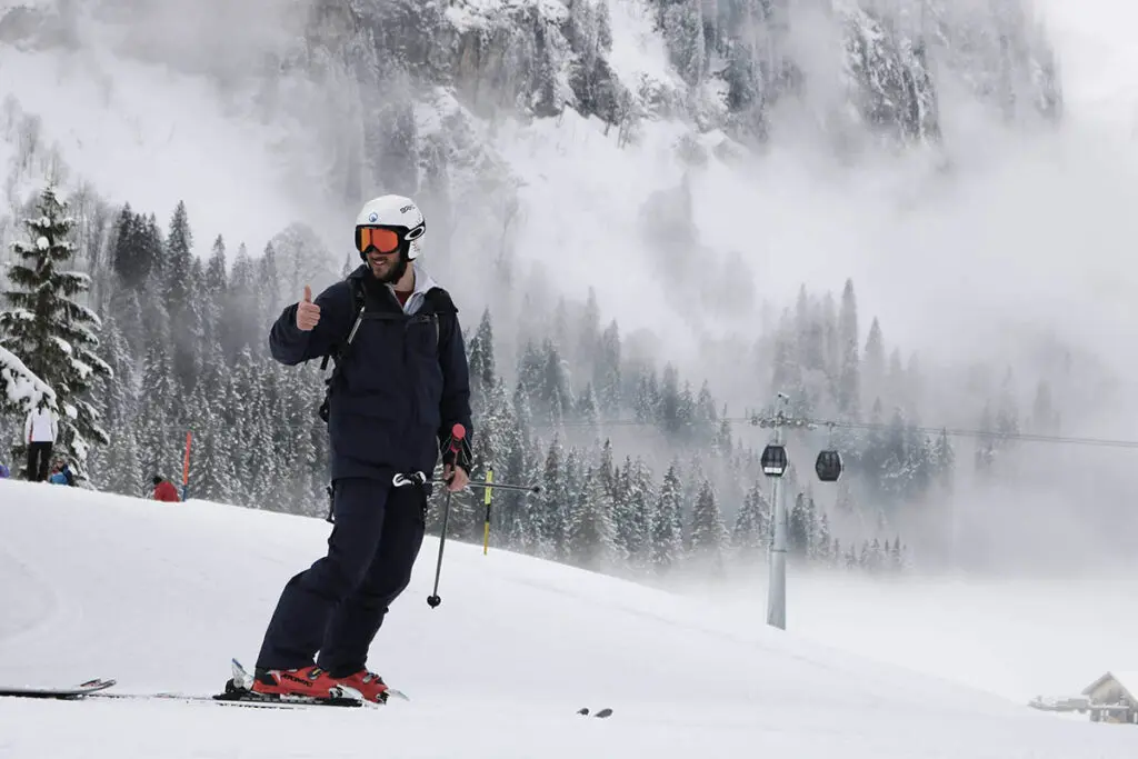 Ski School: Skier gives thumbs up in winter mountain landscape with fresh snow