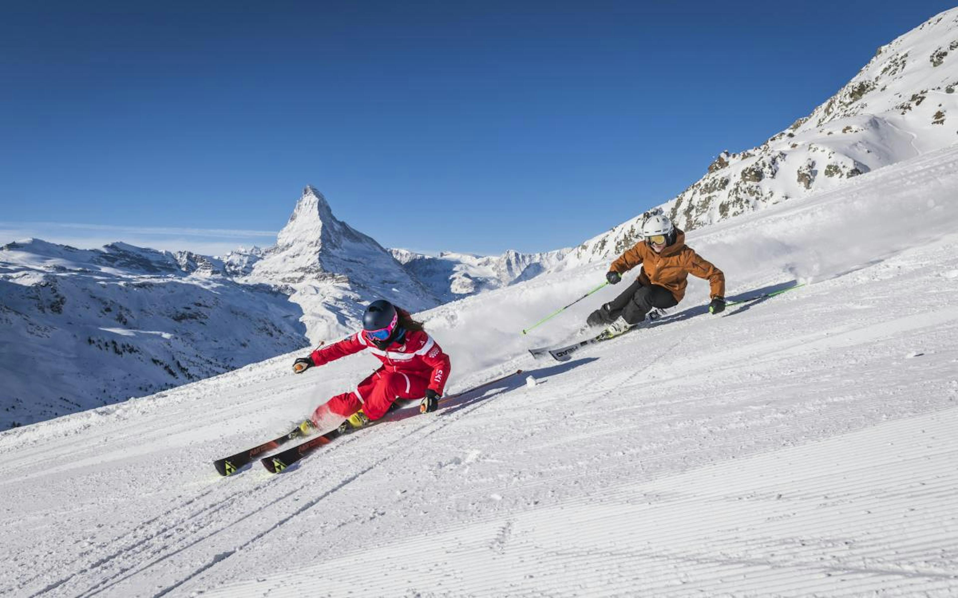 Curso de esquí en Zermatt, dos esquiadores en una pista nevada