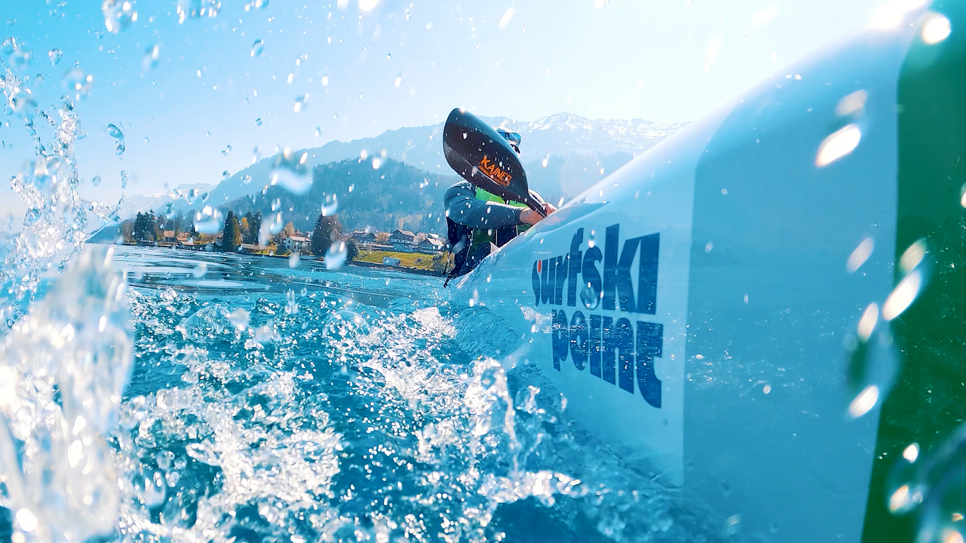 山々の前でクリアな水の上を漕ぐサーフスキーカヤックのライダー