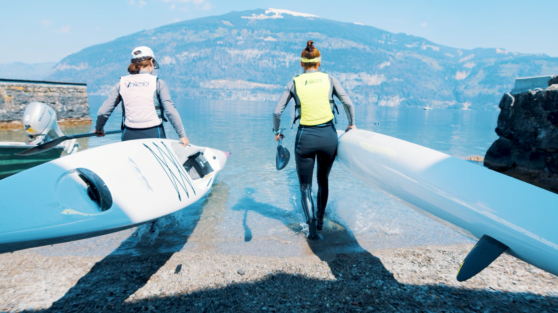 Půjčovna kajaků u Bodamského jezera, dva lidé nesou kajaky do vody