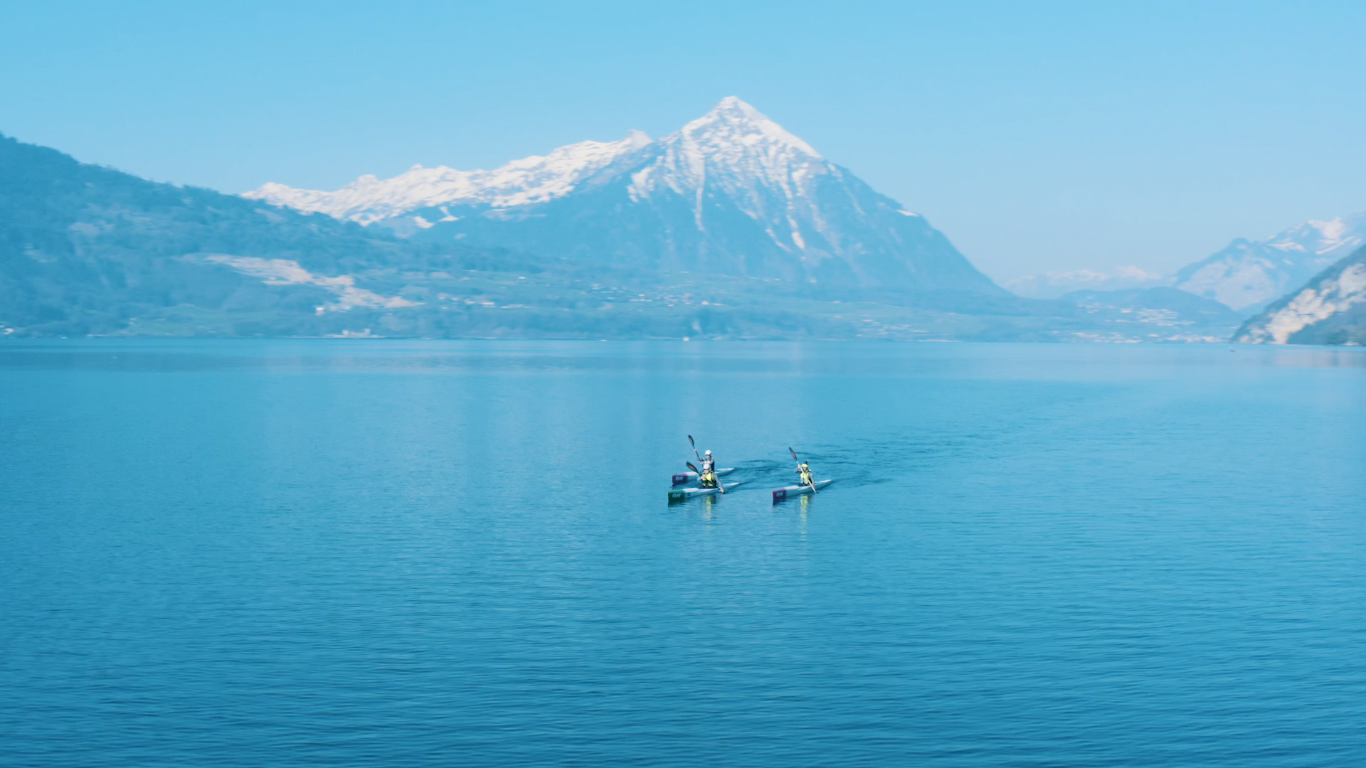 Kajak půjčovna na jezeře před horou Rigi, pádlující osoby na modré vodě