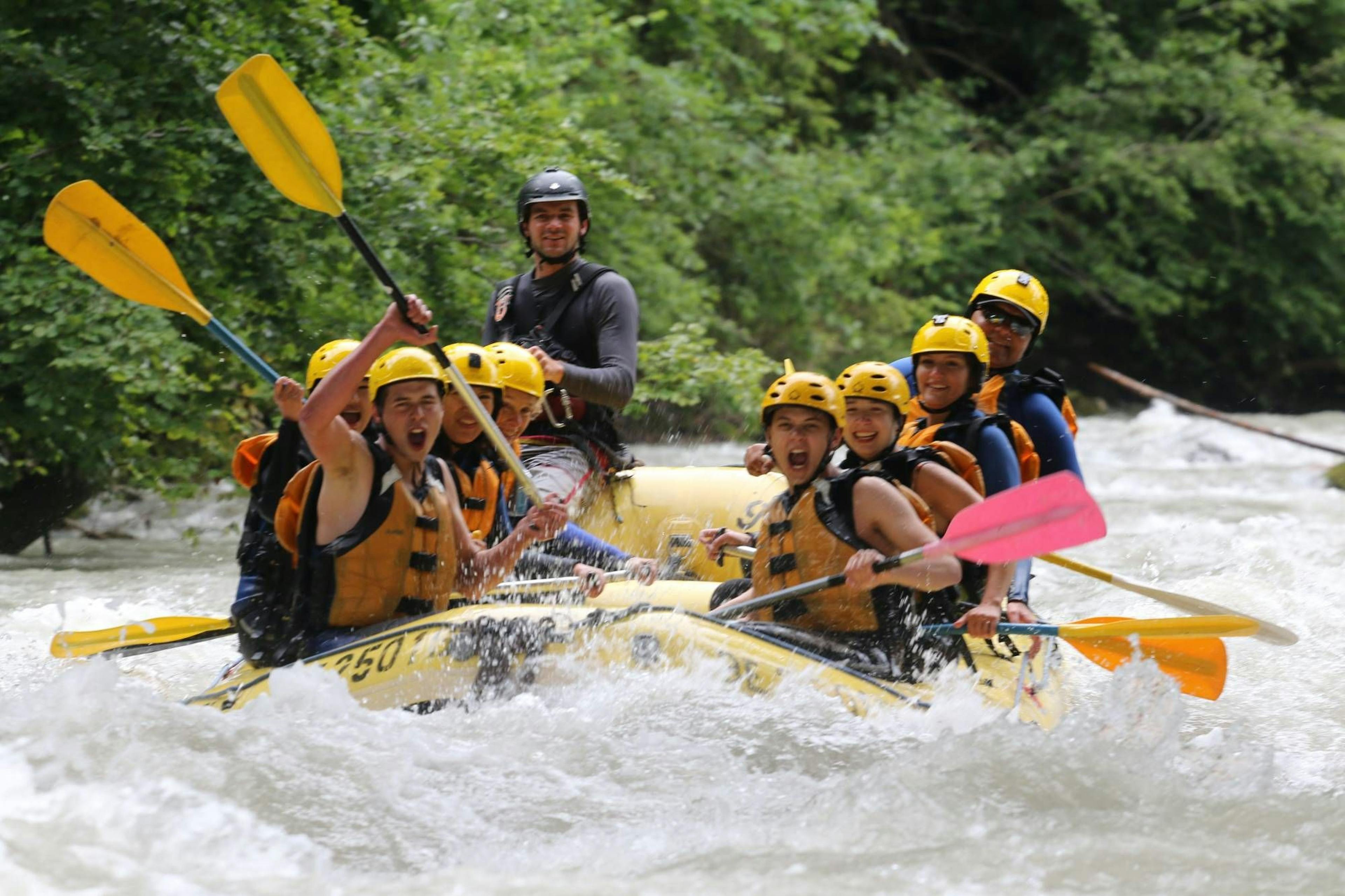 Rafting Simme mit abenteuerlustiger Gruppe in gelben Helmen und Schwimmwesten auf wildem Wasser