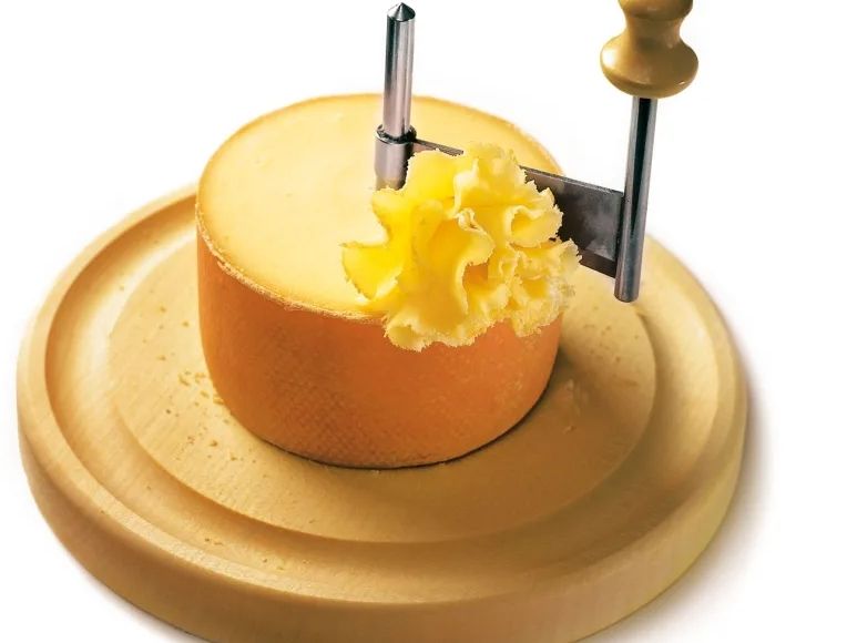 Tête de Moine Käse wird mit einem Käsehobel in feinen Spänen geschnitten.