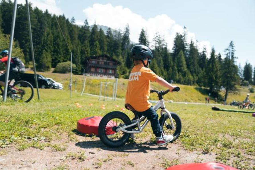 Murmeltier league: Kinder fahren auf Fahrrädern im Sommer in den Bergen und genießen das Abenteuer.