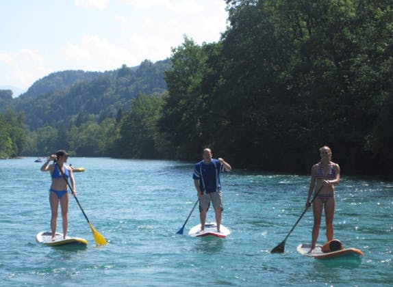 Stand up paddle: 3 personer paddlar på en skimrande vattensjö på sommaren. Perfekt för vattensportentusiaster.