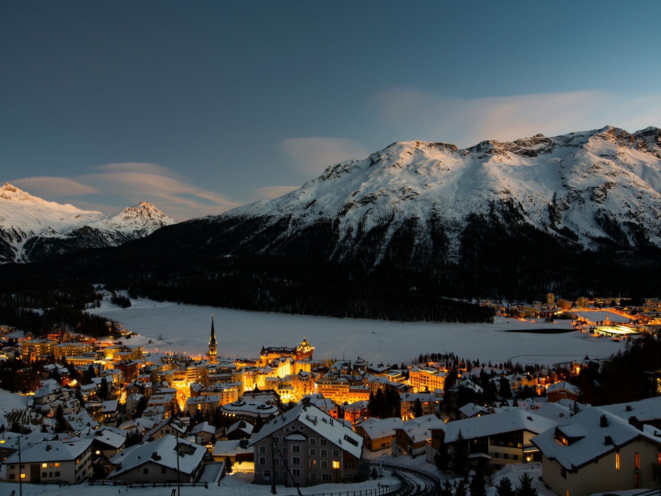 सेंट मॉरिट्ज़: हिमाच्छादित वेंटरलैंड के साथ मनोहारी सर्दियों का दृश्य और रोशनी से जगमग शहर, आल्प्स