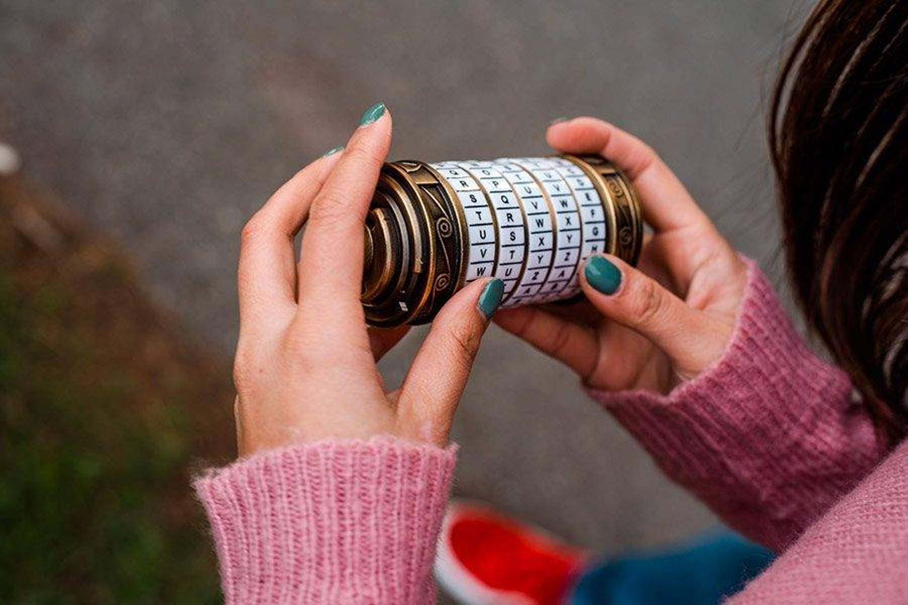 Osoba řeší hádanku s tajemnou číselnou zámkou ve venkovní únikové místnosti.