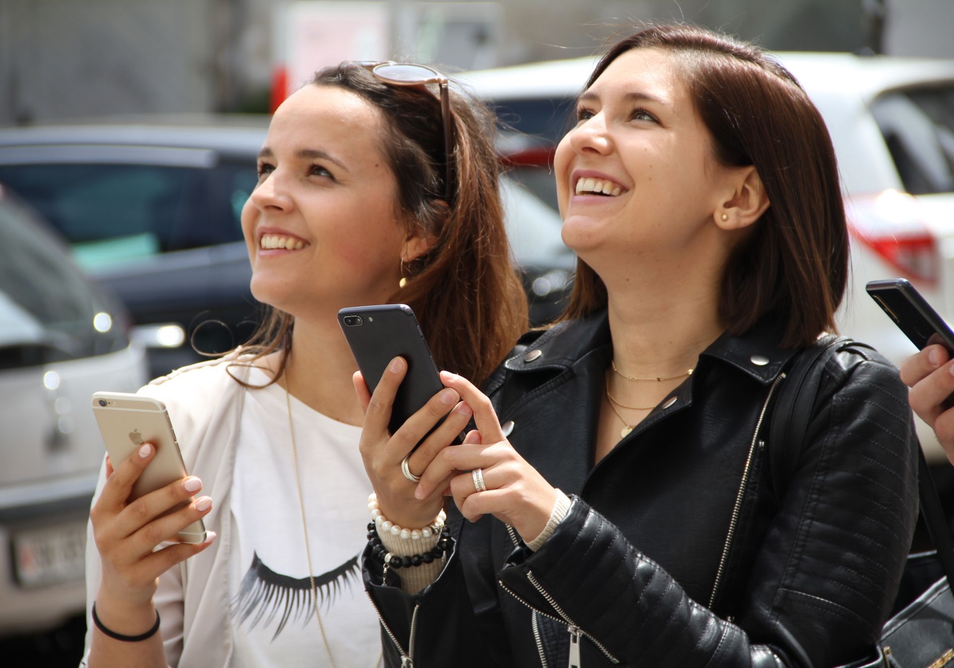 Schnitzeljagd: Zwei lachende Frauen mit Smartphones in der Stadt, die ein Rätsel lösen.